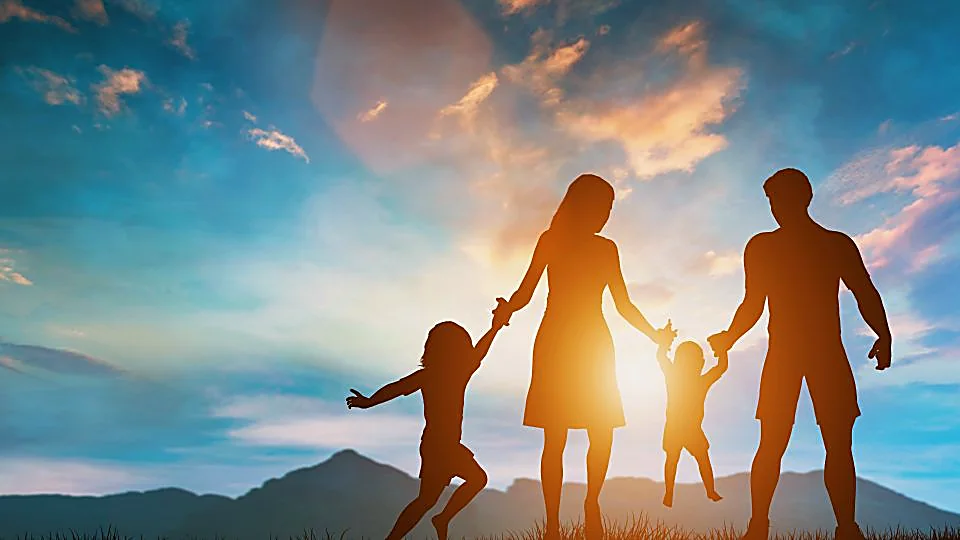 Una famiglia con due bambini cammina controluce al tramonto